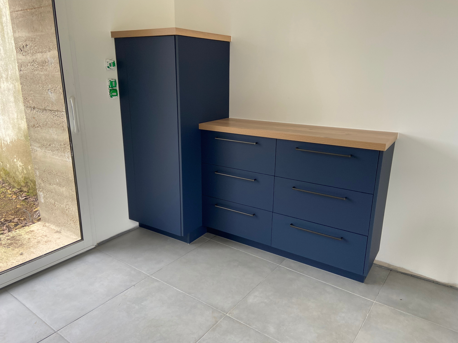 Meuble de cuisine bleu mat avec tiroirs et plan de travail effet bois