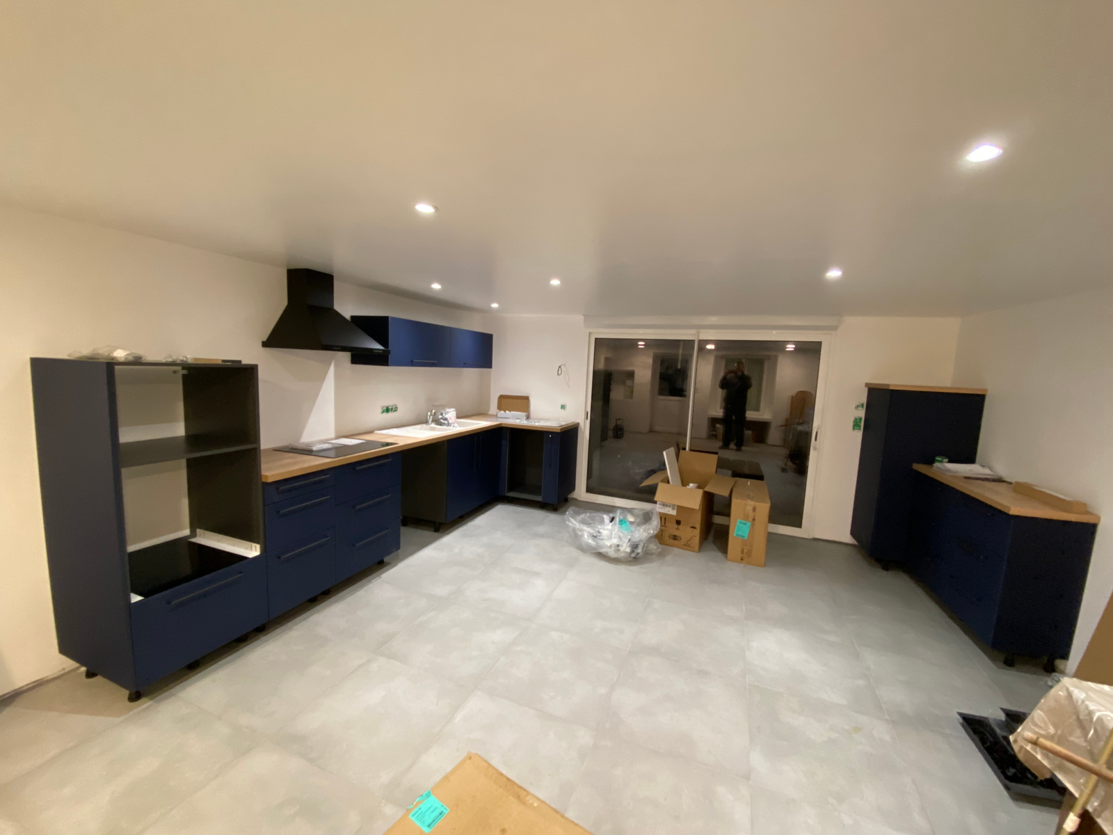 Pose des façades bleu mat et du plan de travail effet bois dans une cuisine