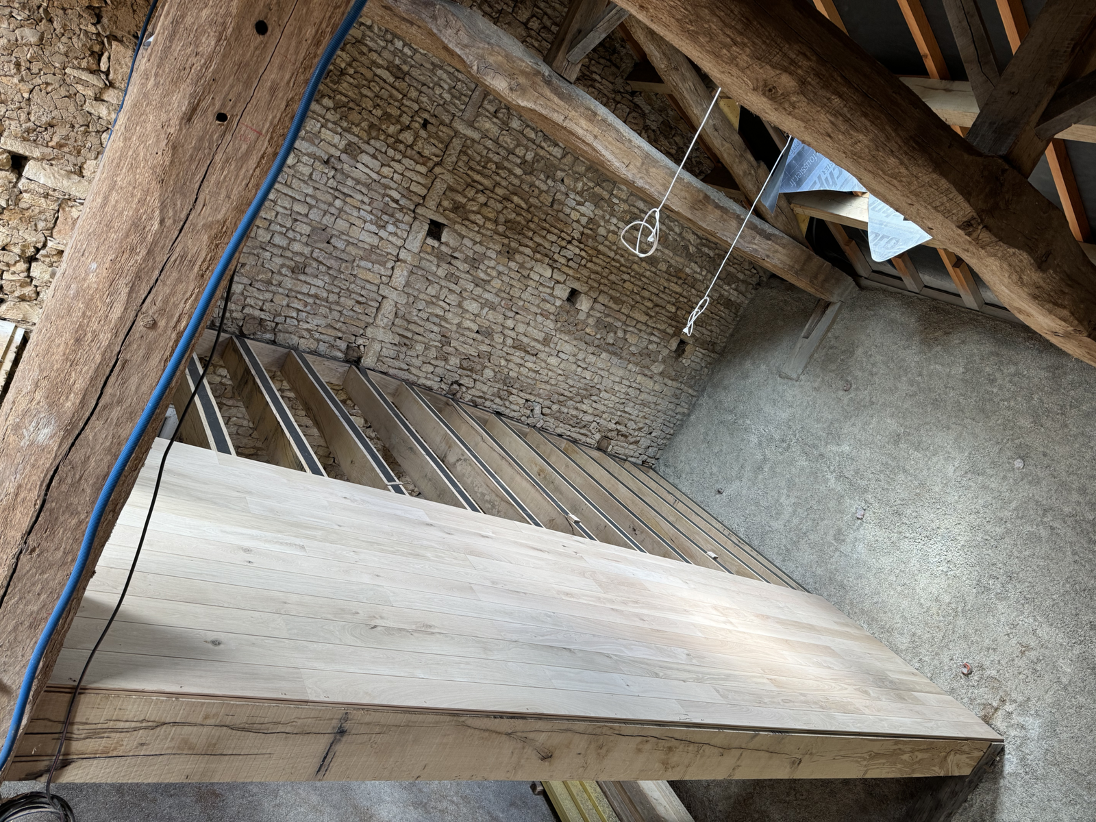 Pose en cours d’un parquet massif en chêne sur solivage à Brux