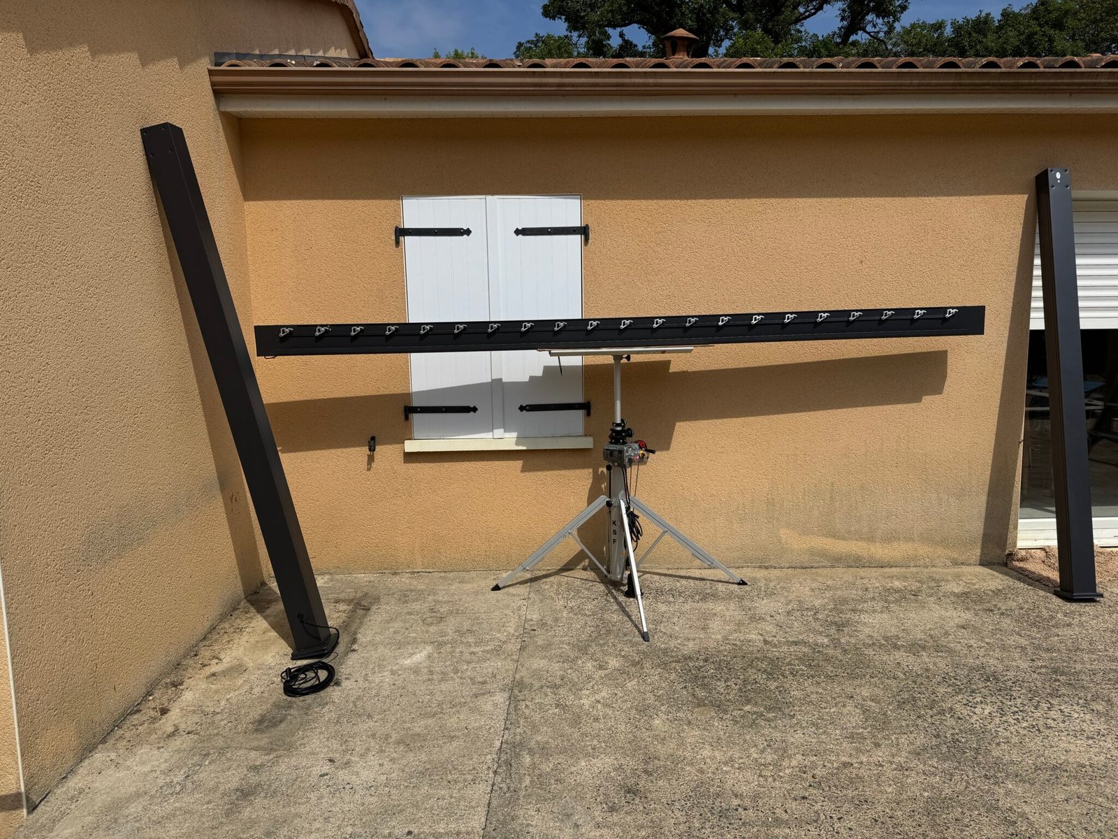 Montage de la structure d’une pergola bioclimatique en aluminium gris anthracite avec un lève store.