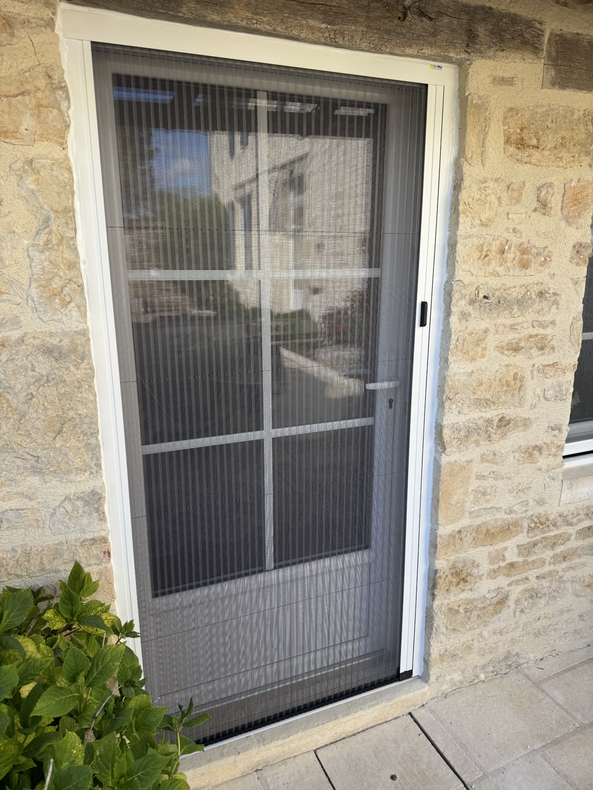 Moustiquaire plissée à chenille sur mesure installée sur une porte