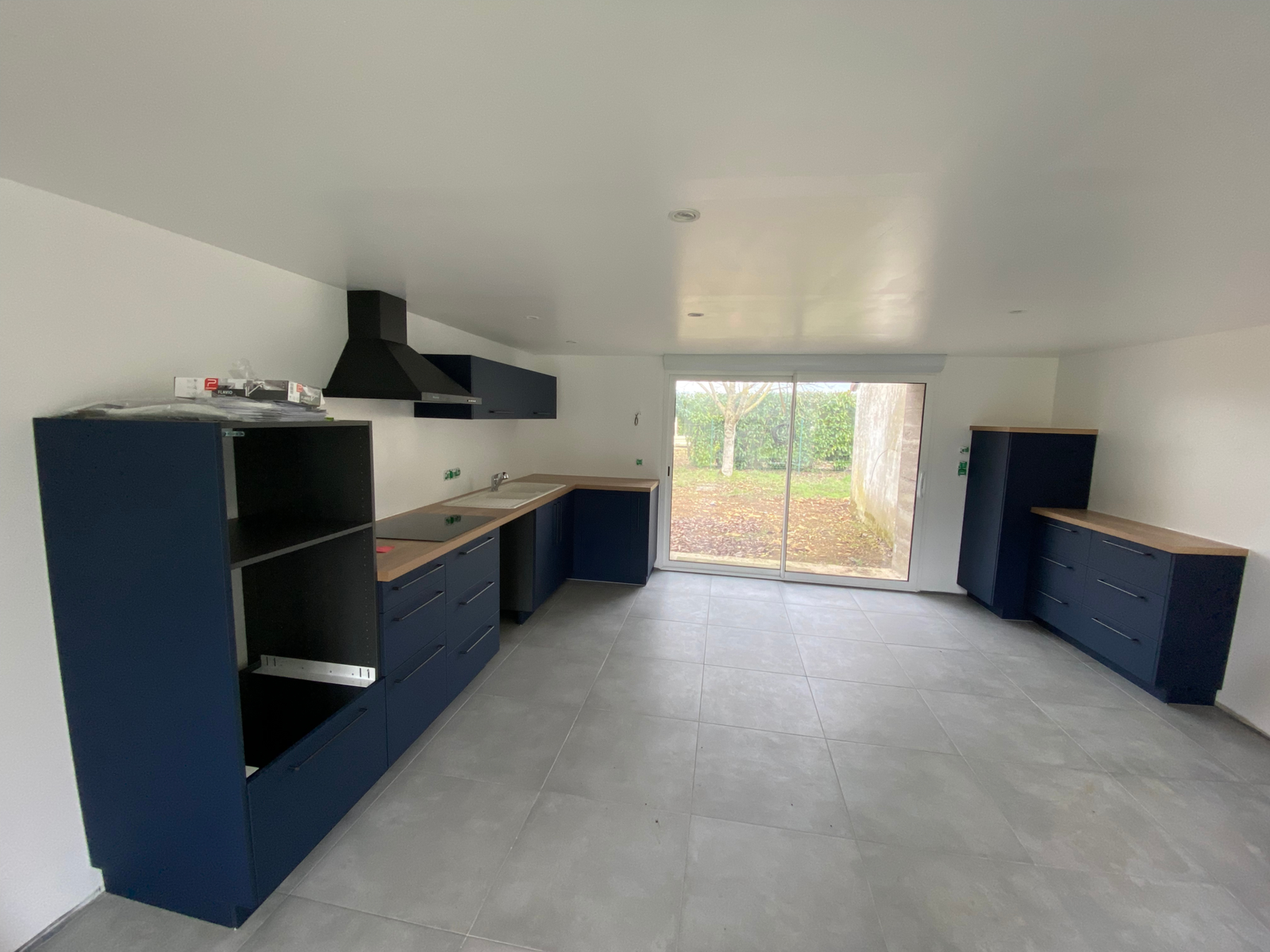 Vue d’ensemble d’une cuisine bleu mat avec plans de travail effet bois à Chaunay