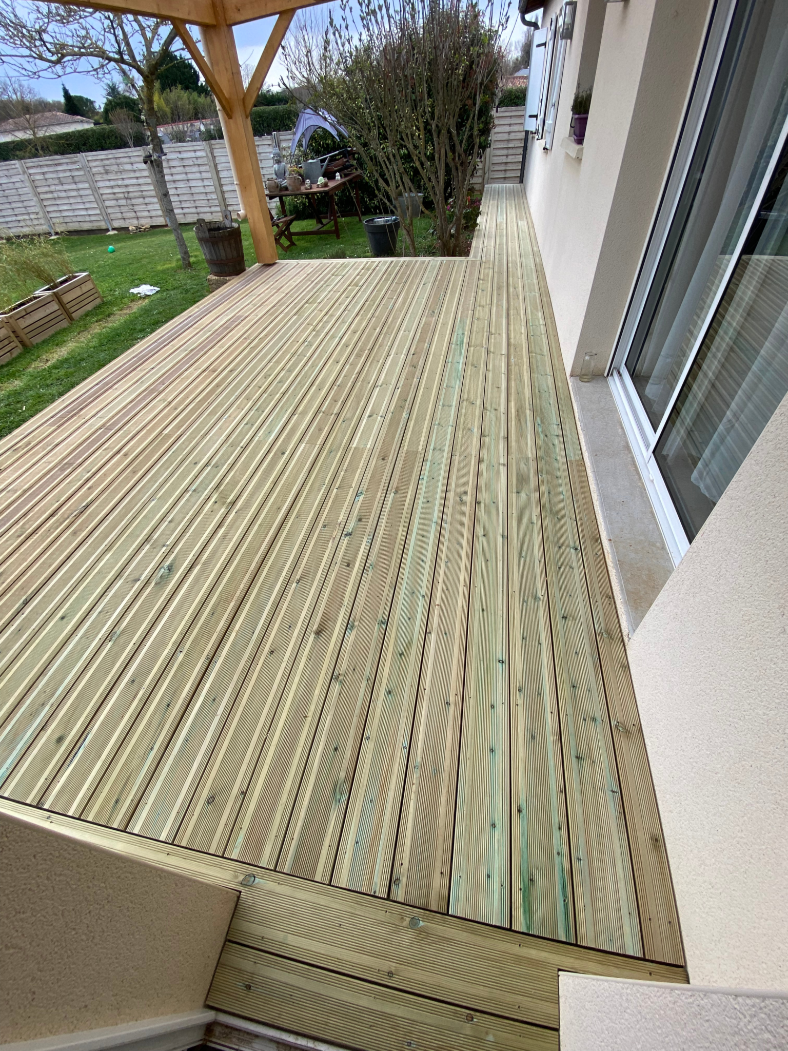 Terrasse en lames de bois posée le long de la façade