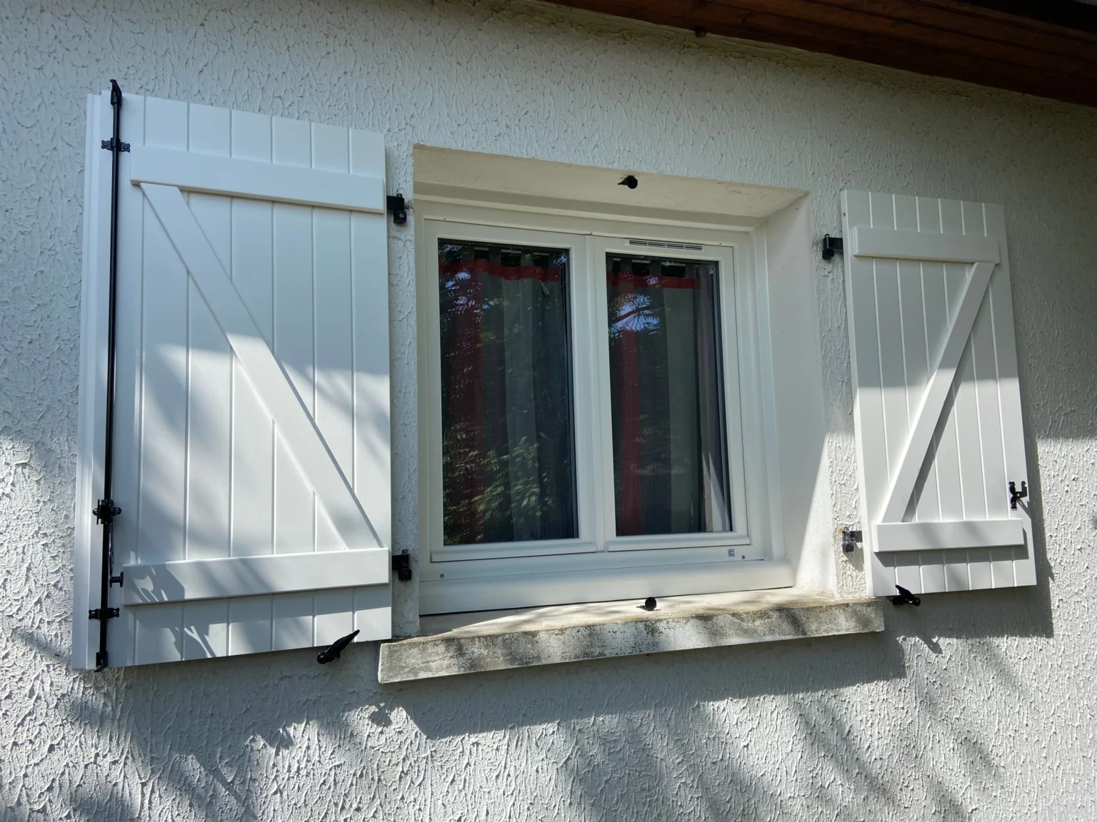 Volets battants en bois blanc ouverts autour d’une fenêtre à Couhé (86)